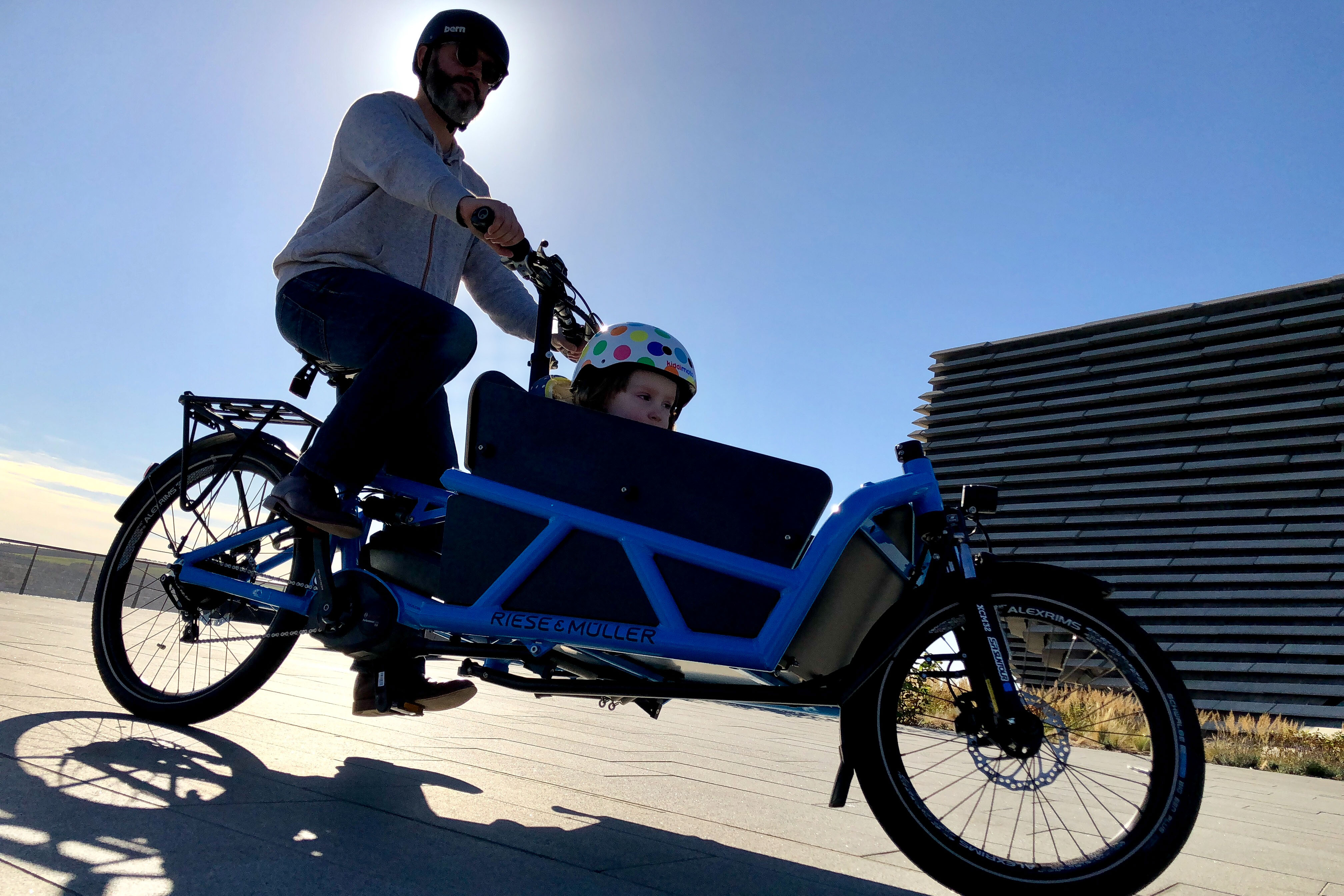 A dad cycling with his daughter in a cargo ebike